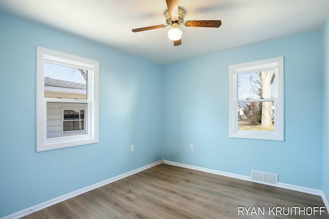 spare room featuring a ceiling fan, wood finished floors, baseboards, and visible vents