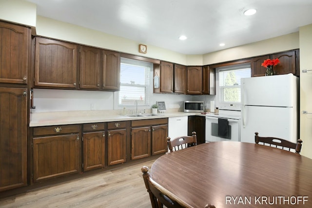 kitchen featuring a sink, white appliances, light wood-style floors, and light countertops