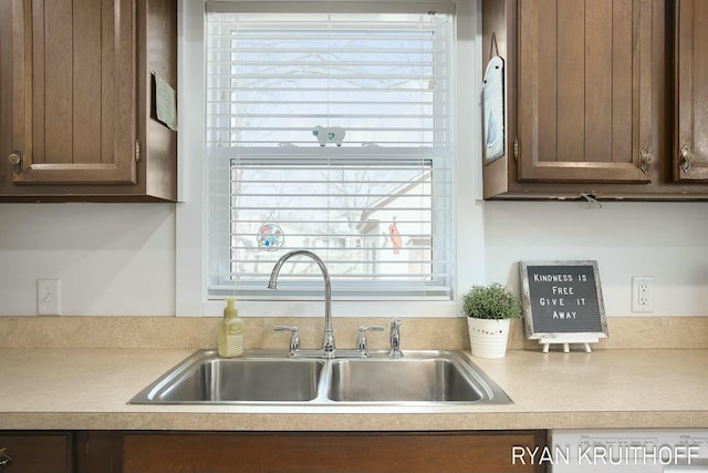 kitchen with a sink, dark brown cabinets, a healthy amount of sunlight, and light countertops