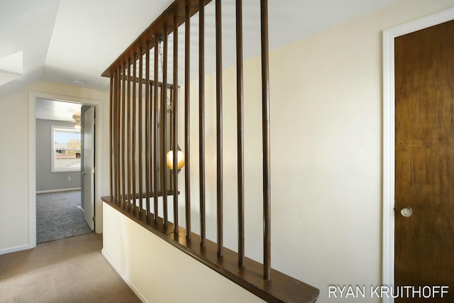 hallway featuring baseboards, carpet, and lofted ceiling