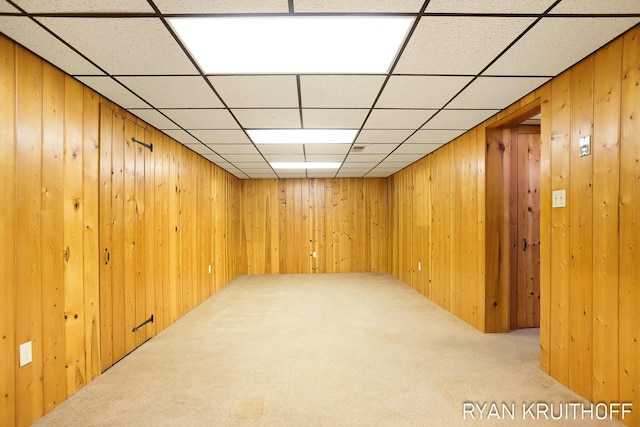 finished below grade area featuring wooden walls, a paneled ceiling, and carpet