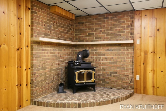 details with a wood stove and a paneled ceiling