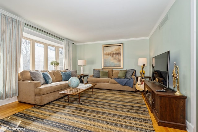 living room with crown molding, light wood-style floors, visible vents, and baseboards