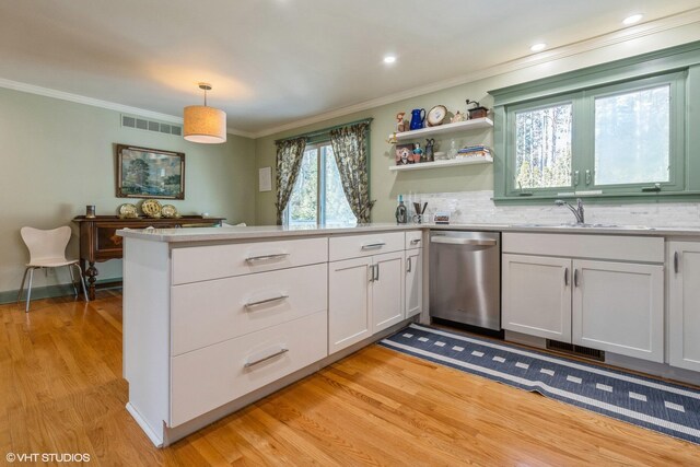 kitchen with a sink, dishwasher, a peninsula, and ornamental molding