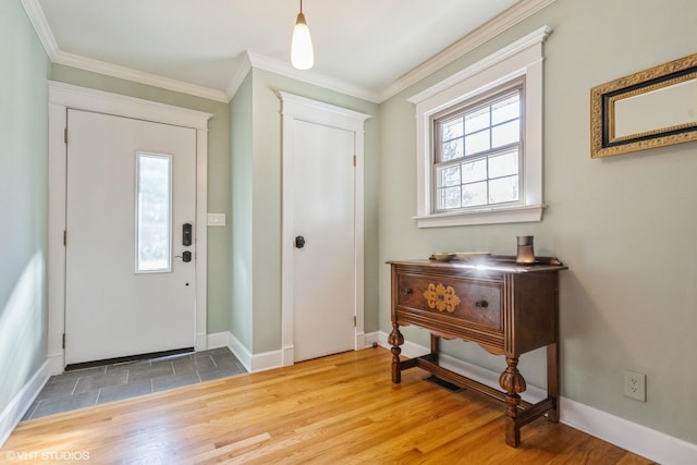 foyer entrance with crown molding, baseboards, and wood finished floors