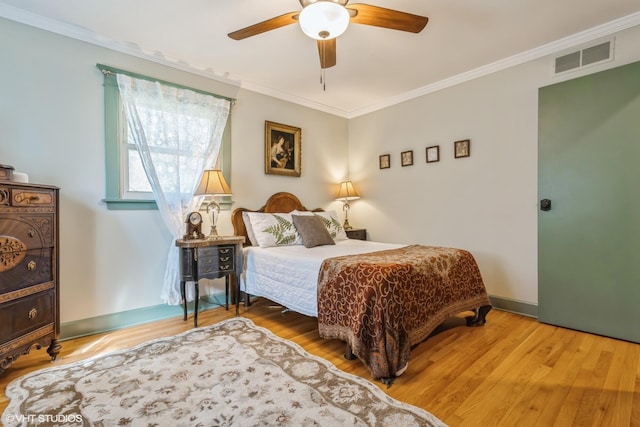 bedroom with visible vents, crown molding, baseboards, and wood finished floors