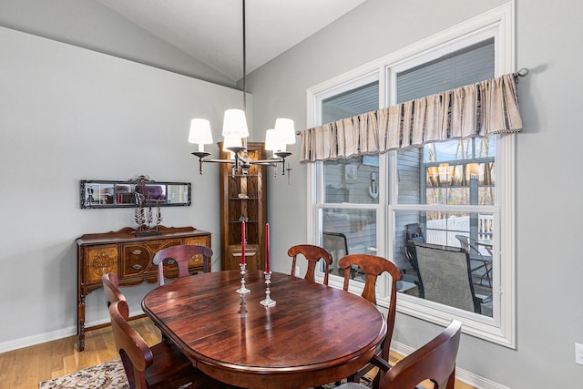 dining room featuring baseboards, lofted ceiling, an inviting chandelier, and wood finished floors