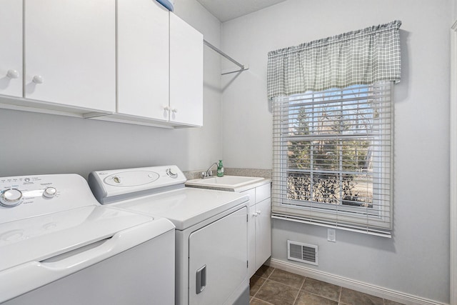 washroom featuring visible vents, a sink, washer and dryer, cabinet space, and dark tile patterned flooring