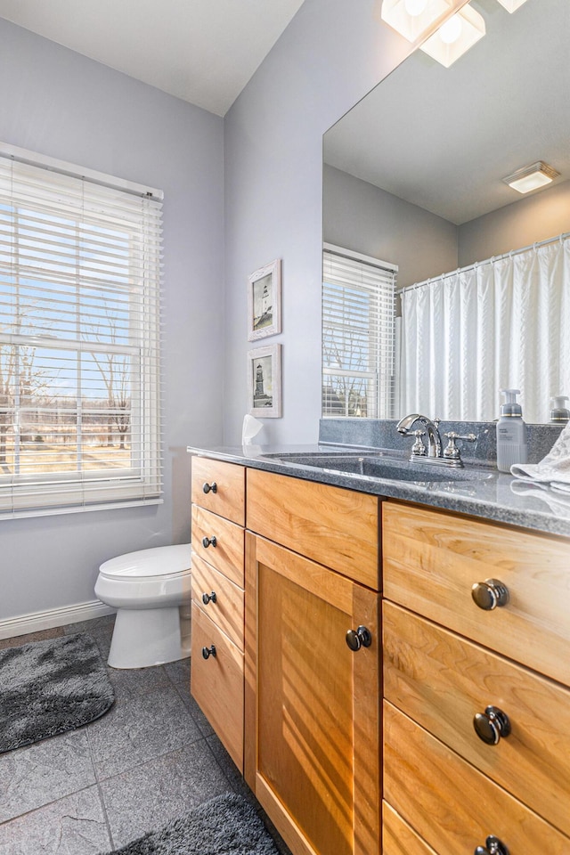 bathroom featuring a wealth of natural light, toilet, a skylight, and baseboards