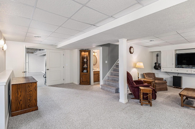 finished below grade area with stairway, a paneled ceiling, light colored carpet, and baseboards