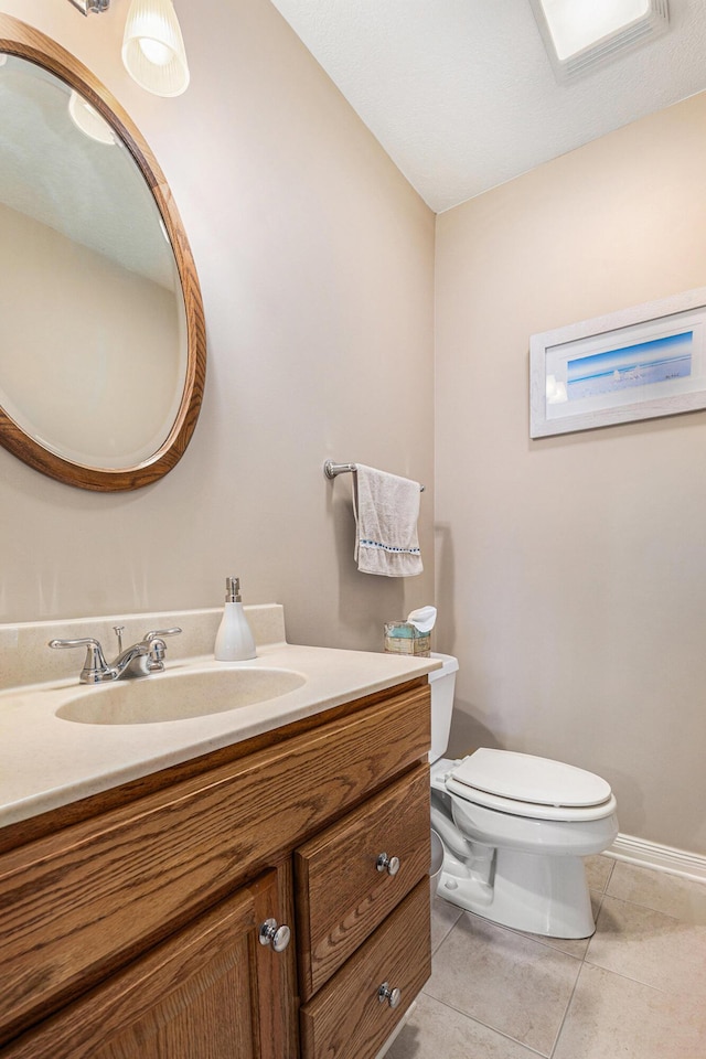 half bathroom with tile patterned flooring, toilet, vanity, and baseboards