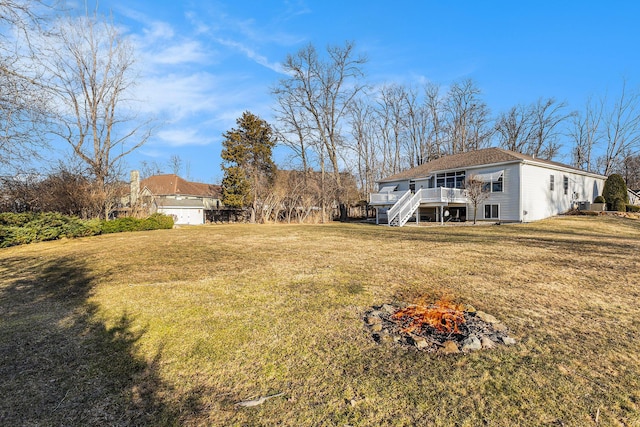 view of yard with stairway, a fire pit, and a wooden deck