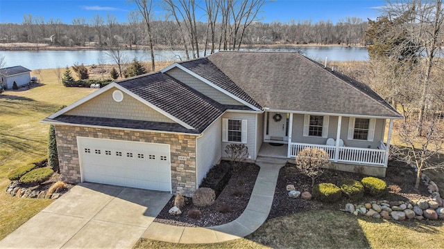 single story home featuring covered porch, driveway, a garage, and a water view