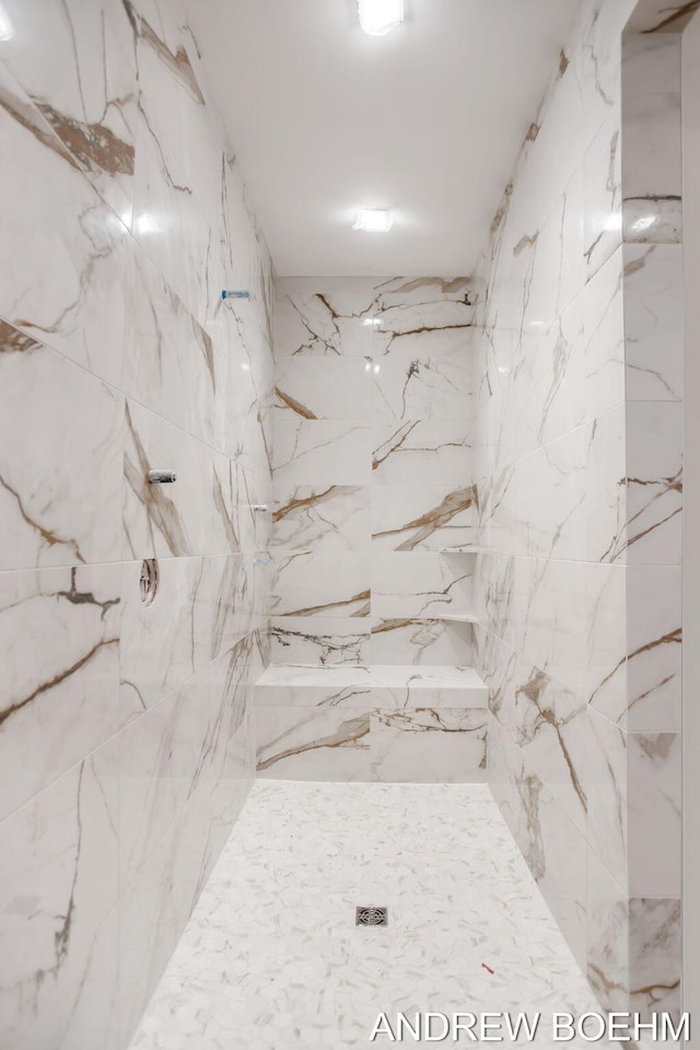 bathroom with a marble finish shower and stone wall