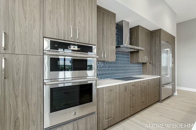 kitchen featuring decorative backsplash, wall chimney exhaust hood, modern cabinets, and appliances with stainless steel finishes