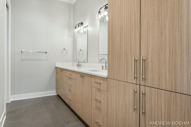 bathroom featuring a sink, baseboards, double vanity, and tile patterned floors