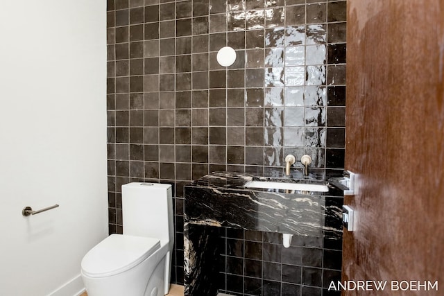 half bath with a sink, toilet, and tile walls