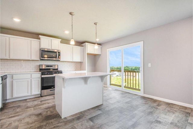 kitchen with light wood-style flooring, a center island, stainless steel appliances, light countertops, and decorative backsplash