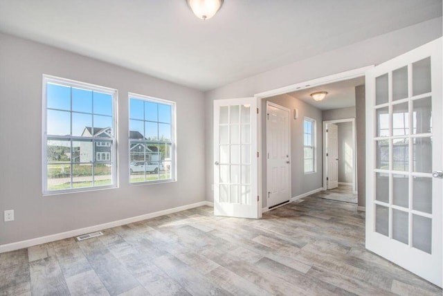 empty room with visible vents, french doors, baseboards, and wood finished floors