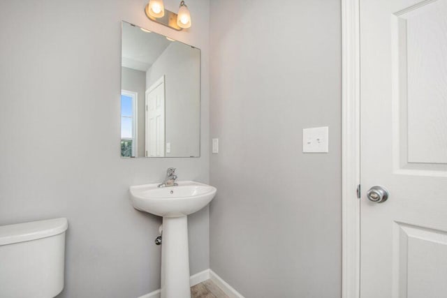 bathroom featuring toilet, baseboards, and a sink