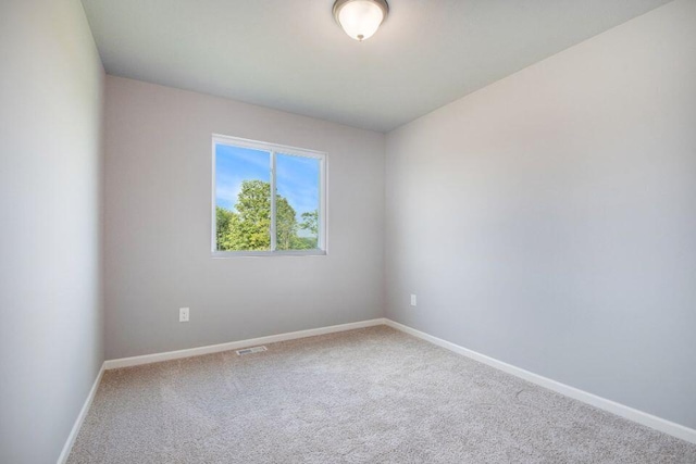 carpeted empty room featuring baseboards and visible vents