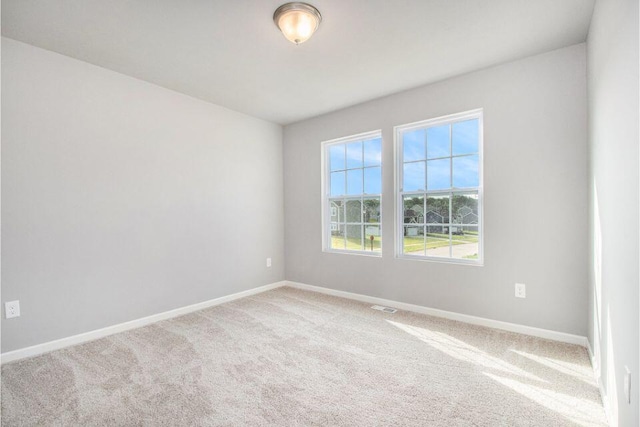 spare room featuring visible vents, baseboards, and light colored carpet