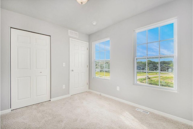 unfurnished bedroom featuring visible vents, carpet flooring, baseboards, and multiple windows