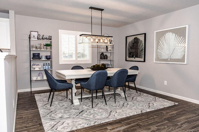 dining room with dark wood finished floors, an inviting chandelier, and baseboards