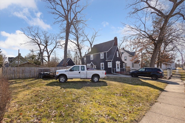 view of home's exterior with a yard, a residential view, a chimney, and fence