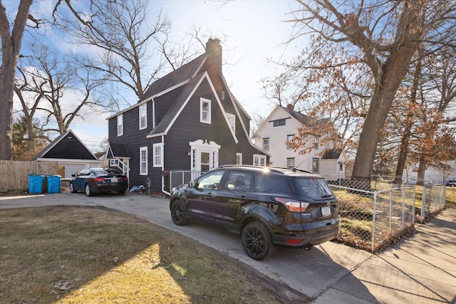 view of front of property featuring concrete driveway, fence, a front lawn, and a chimney