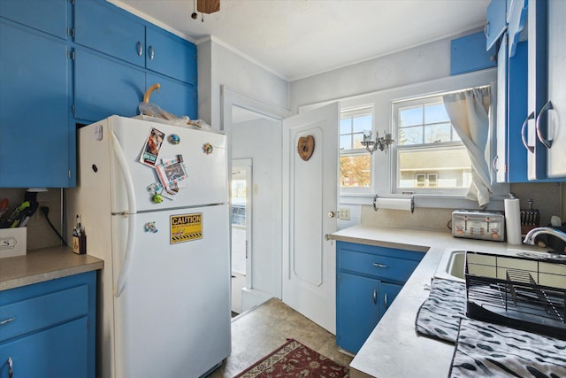 kitchen featuring blue cabinets, light countertops, and freestanding refrigerator