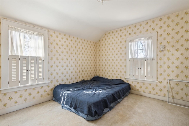 bedroom with baseboards, carpet floors, lofted ceiling, and wallpapered walls