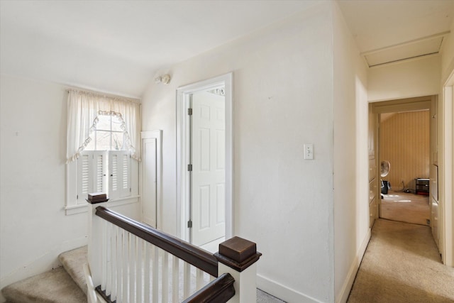 corridor featuring light colored carpet and baseboards