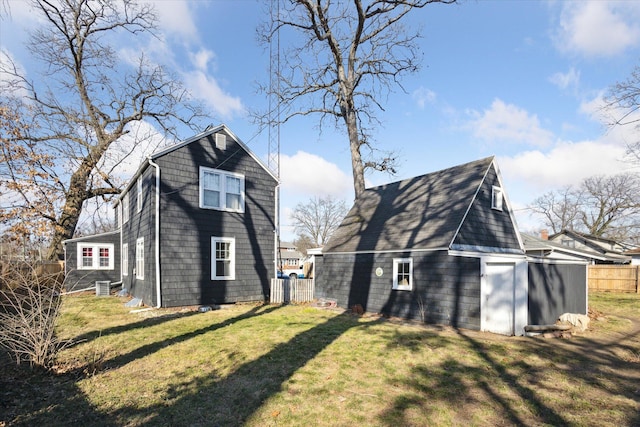 view of side of home featuring an outbuilding, central AC unit, a lawn, and fence