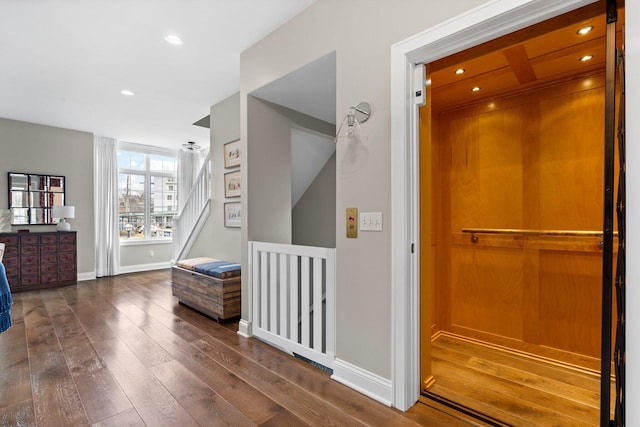 corridor featuring elevator, dark wood-style floors, recessed lighting, and baseboards