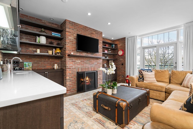 living area featuring a brick fireplace, built in shelves, and recessed lighting