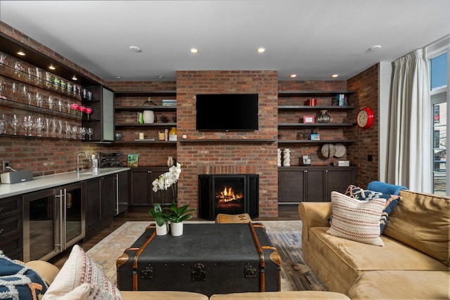 living room featuring a brick fireplace, beverage cooler, wet bar, and brick wall