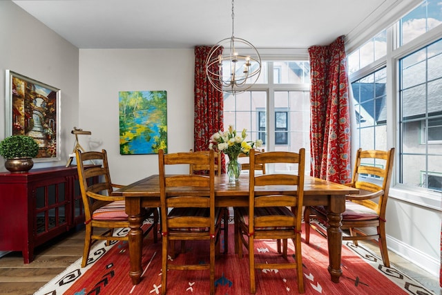 dining space featuring baseboards, an inviting chandelier, and wood finished floors