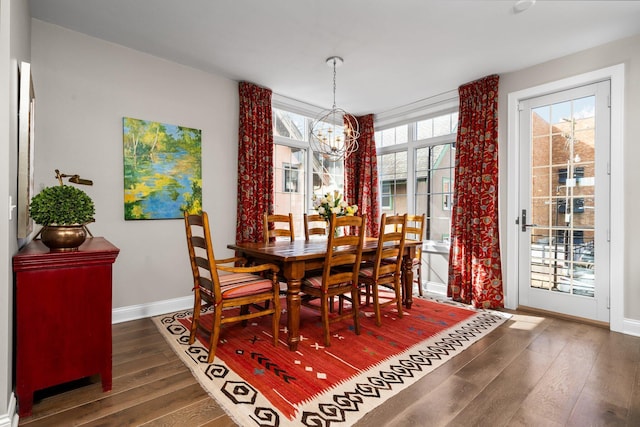 dining area with baseboards, a notable chandelier, and hardwood / wood-style flooring