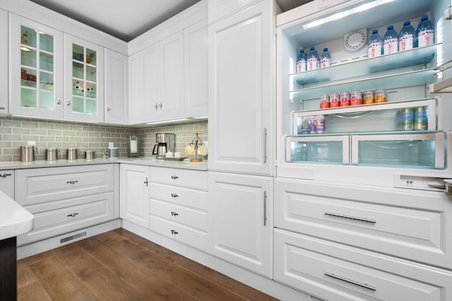 kitchen with light countertops, white cabinets, dark wood-style floors, and backsplash