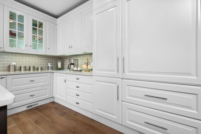 kitchen with glass insert cabinets, tasteful backsplash, and white cabinetry