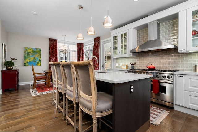 kitchen with backsplash, high end stove, wall chimney range hood, and a sink