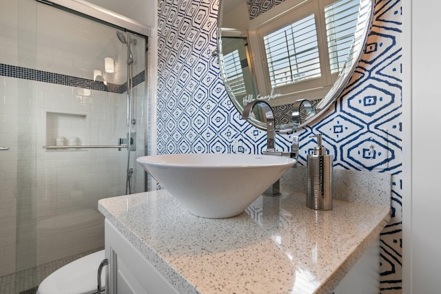 bathroom featuring toilet, a stall shower, vanity, and tile walls