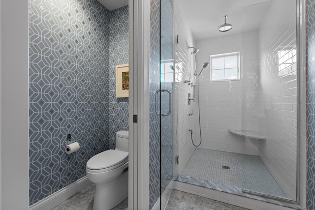 bathroom featuring baseboards, toilet, and a shower stall