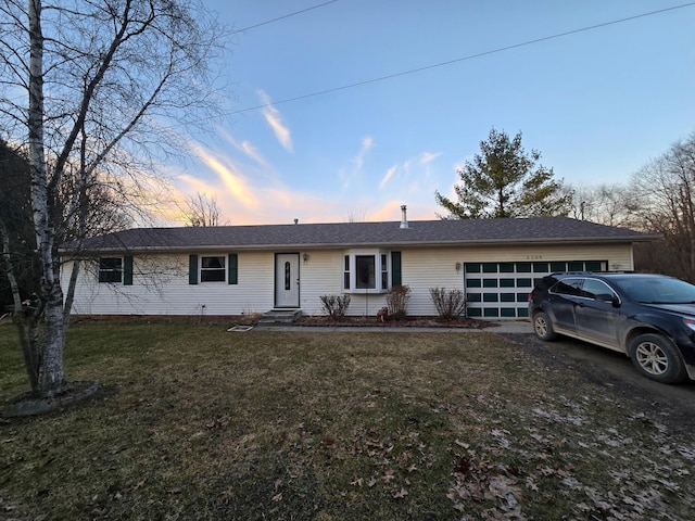 single story home with a garage, a lawn, and driveway