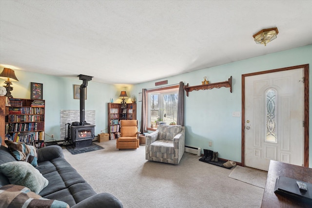 living area with a baseboard heating unit, a wood stove, carpet, and a textured ceiling