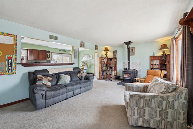 living room featuring visible vents, a wood stove, baseboards, and carpet floors