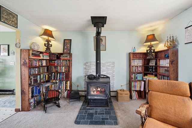 sitting room featuring a baseboard heating unit, a wood stove, and carpet floors