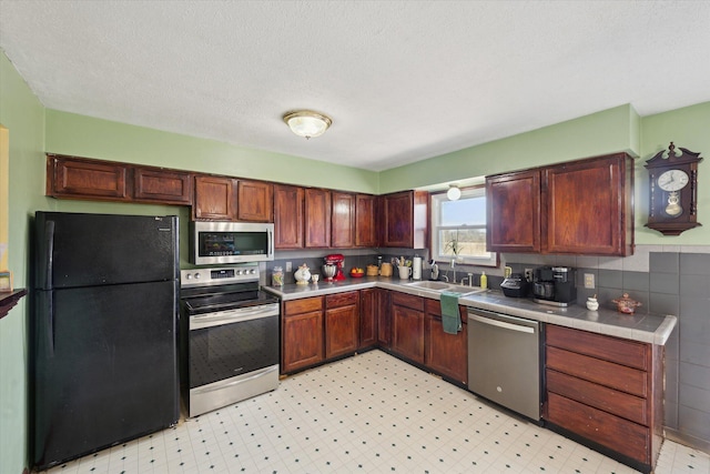 kitchen featuring a sink, stainless steel appliances, light floors, and a textured ceiling