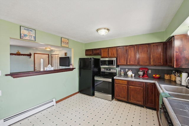 kitchen featuring a sink, backsplash, light floors, stainless steel appliances, and baseboard heating